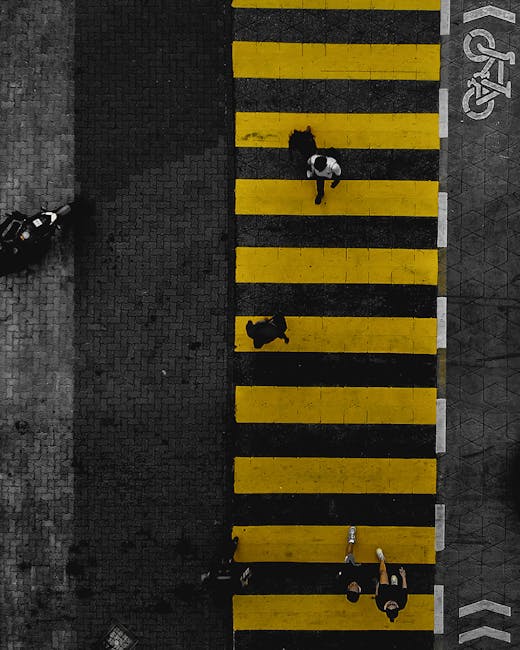 pexels-photo-6109449-6109449 Bird's-eye view of people crossing a striking yellow-striped crosswalk, pavement, and bike lane.